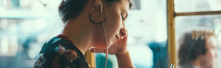 A lady listens to headphones on a bus